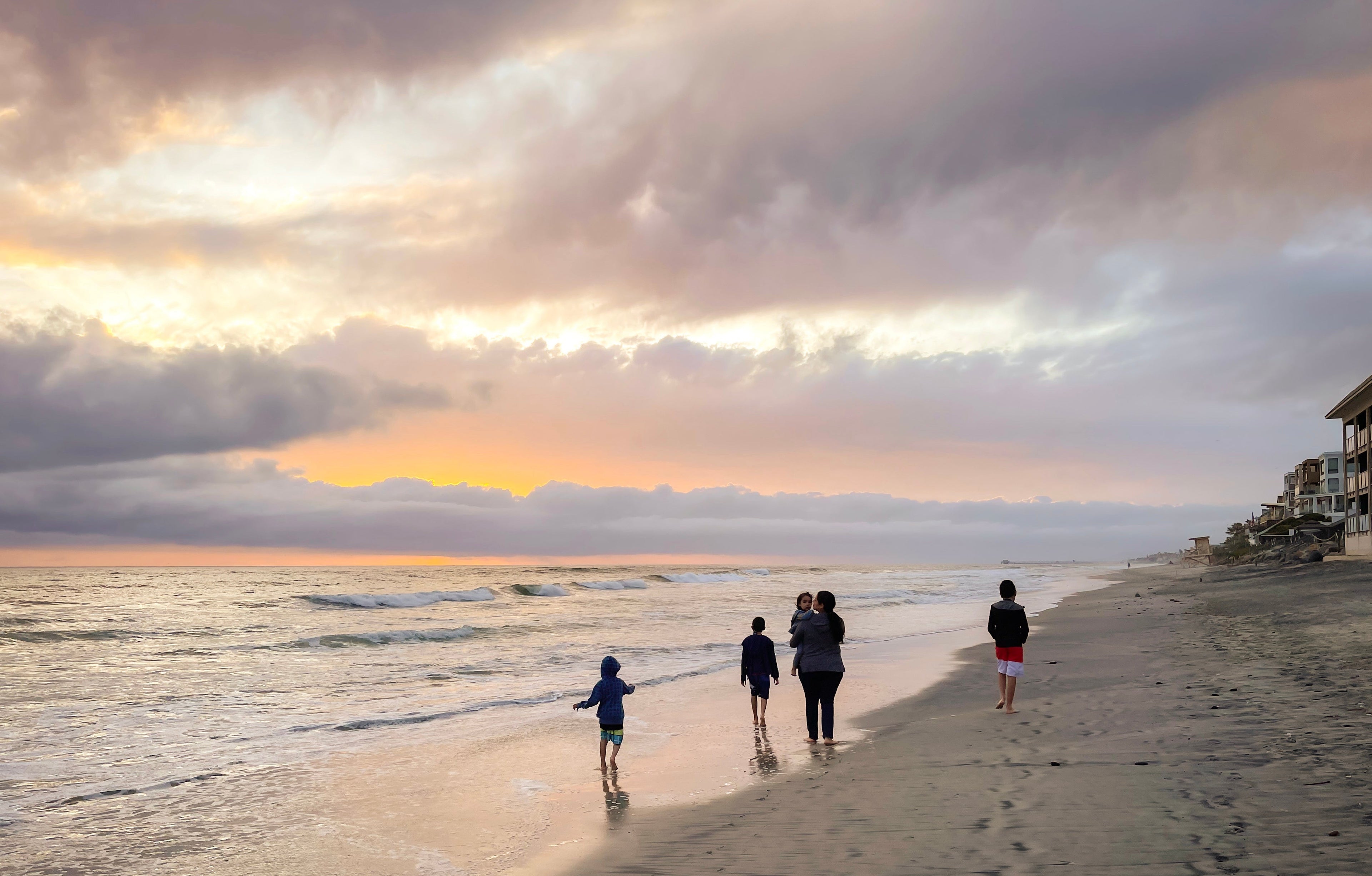People walking on a beach with a cloudy sky and sunset with Southern Californian Artist Maria Rangel Cardenas